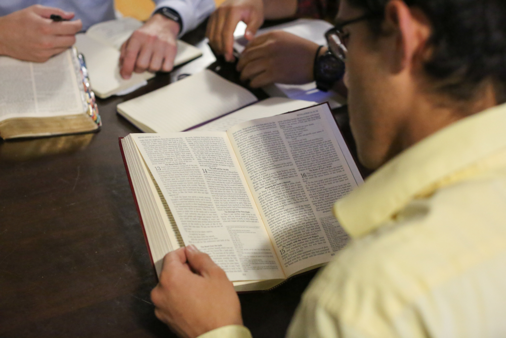 A young Catholic man praying over sacred scripture.